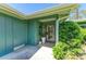 Inviting front porch featuring a secured front door, decorative plants, and neutral tiling and green siding at 1622 Stafford Ln # 1205, Sarasota, FL 34232