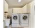 Bright laundry room with washer, dryer, utility sink, and storage cabinets at 1622 Stafford Ln # 1205, Sarasota, FL 34232