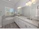 Bathroom with dual sinks, white cabinets, granite countertop, tub, and plenty of counter space at 212 Milan W Ave # 1, Venice, FL 34285