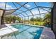 Enclosed pool area featuring a lounge area and view of the lush greenery and water at 2177 Weaver Bird Ln, Venice, FL 34292