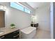 Bright bathroom featuring a soaking tub, stylish vanity, and window at 221 Cosmopolitan Ct, Sarasota, FL 34236