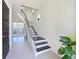 Elegant staircase featuring dark wood treads, metal railings, modern lighting, and light tile floors at 221 Cosmopolitan Ct, Sarasota, FL 34236