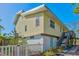 Side view of a charming yellow home with stairs leading to an elevated entry at 234 85Th St, Holmes Beach, FL 34217