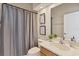 Inviting bathroom with decorative art, a single sink vanity, and shower with a light gray curtain at 24017 Peppercorn Rd, Punta Gorda, FL 33955