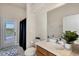 Well-lit bathroom featuring a single sink, black shower curtain, and door leading to outdoor pool area at 24017 Peppercorn Rd, Punta Gorda, FL 33955