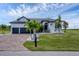 Charming home featuring a brick driveway, gray shutters, and a perfectly manicured lawn at 24017 Peppercorn Rd, Punta Gorda, FL 33955