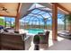 Screened-in outdoor pool area with comfortable seating, lush landscaping, and a view of the surrounding community at 24017 Peppercorn Rd, Punta Gorda, FL 33955