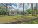 Quaint exterior elevation featuring mature trees, lush lawn, and a peaceful residential setting at 275 Burke Rd, Venice, FL 34293