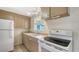 Compact kitchen featuring white appliances, tan cabinets, and a window offering natural light at 275 Burke Rd, Venice, FL 34293