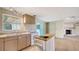 Bright kitchen with island, tan cabinets, white appliances, and easy access to a screened lanai and living room at 275 Burke Rd, Venice, FL 34293
