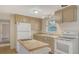 Cozy kitchen with tan cabinets, white appliances, and tile flooring, enhanced by natural light at 275 Burke Rd, Venice, FL 34293