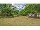 A view of a grassy vacant property lot filled with mature trees under cloudy skies at 275 Burke Rd, Venice, FL 34293