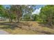 View of a grassy vacant property lot filled with mature trees and a wooden fence on a sunny day at 275 Burke Rd, Venice, FL 34293