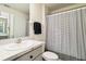 Well-lit bathroom with a single sink vanity, toilet, and shower with a striped curtain at 2812 Rock Sound St, Bradenton, FL 34208