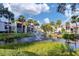 Beautiful community view with a peaceful pond, fountain, palm trees, and well-maintained buildings under a bright sky at 3251 Beneva Rd # 104, Sarasota, FL 34232