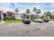 Exterior view of a community with cars parked in a lot, lush greenery, palm trees, and a building with red tile roofing at 3251 Beneva Rd # 104, Sarasota, FL 34232