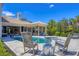 Backyard patio area with swimming pool, spa, outdoor kitchen, rocking chairs, and manicured tropical landscaping at 3432 Founders Club Dr, Sarasota, FL 34240