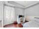 Cozy bedroom with a workstation, featuring hardwood floors and natural light from the sheer curtained window at 3432 Founders Club Dr, Sarasota, FL 34240