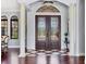Elegant foyer with detailed double doors, marble floors, columns, and transom window at 3432 Founders Club Dr, Sarasota, FL 34240