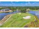 Aerial view of a golf course with a lake, sand traps, and golfers enjoying the course, with a house in the background at 3432 Founders Club Dr, Sarasota, FL 34240