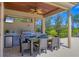 Covered outdoor dining area features a full kitchen, ceiling fan, television, and seating for six people at 3432 Founders Club Dr, Sarasota, FL 34240
