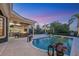 Outdoor living area with covered patio, outdoor kitchen, and a stunning pool at twilight at 3432 Founders Club Dr, Sarasota, FL 34240