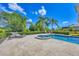 Sparkling swimming pool and spa with lounge chairs, surrounded by lush landscaping and stone paved deck at 3432 Founders Club Dr, Sarasota, FL 34240
