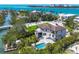 Stunning aerial view of a waterfront home with a pool and lush landscaping near a beautiful ocean at 3465 Gulfmead Dr, Sarasota, FL 34242