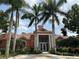 Beautiful clubhouse exterior with a red tile roof and large white pillars, surrounded by lush green landscaping and tall palm trees at 4166 Central Sarasota Pkwy # 535, Sarasota, FL 34238