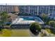 Aerial view showcasing a community pool with lounge chairs, surrounded by a pond and buildings at 4186 Heron Way # B-219, Bradenton, FL 34205