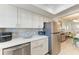 Bright kitchen with white cabinetry, stainless steel refrigerator, and mosaic tile backsplash, open to dining room at 4186 Heron Way # B-219, Bradenton, FL 34205