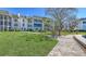 Well-maintained building with mature landscaping, sidewalk, and lush green grass at 4380 Exeter Dr # H202, Longboat Key, FL 34228