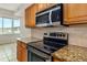 Close-up kitchen shot featuring granite countertops, a black stove top, and a stainless steel microwave at 4885 1St Ne St # 308, St Petersburg, FL 33703