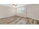 Open-concept living room featuring modern laminate flooring, a ceiling fan, and a storm door with windows at 4885 1St Ne St # 308, St Petersburg, FL 33703