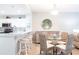 Dining area with a round glass table, woven chairs, and a view into the modern kitchen with bar seating at 6334 Grand Oak Cir # 202, Bradenton, FL 34203