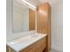 Modern bathroom features a wood vanity with marble countertop, mirrored wall, and tall storage cabinet at 7200 Chameleon Way, Sarasota, FL 34241