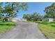 Long driveway to modern home with guest house surrounded by mature trees and green lawn at 7200 Chameleon Way, Sarasota, FL 34241