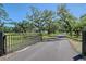 Long driveway leading to an estate with an iron gate and mature trees at 7200 Chameleon Way, Sarasota, FL 34241