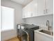 Laundry room with new washer and dryer and white cabinets at 7200 Chameleon Way, Sarasota, FL 34241