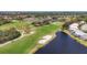 Aerial view showcasing a golf course featuring a pristine lake, manicured greens and houses in a gated community at 8718 Grey Oaks Ave, Sarasota, FL 34238