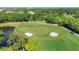 Scenic golf course view showcasing a green with bunkers and a pond, surrounded by lush vegetation and palm trees at 8718 Grey Oaks Ave, Sarasota, FL 34238