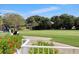 Scenic view of the golf course with a golf cart and vibrant red flowers in the foreground at 8718 Grey Oaks Ave, Sarasota, FL 34238