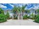 Bright two-story condo featuring tropical landscaping, concrete driveway and white facade at 902 Addington Ct # 202, Venice, FL 34293