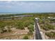 Aerial view of a road heading to a beach overlooking calm ocean waters and lush green tropical plants at 1156 Lemon Bay Dr, Venice, FL 34293
