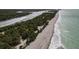 An aerial view captures a boat-lined waterway meeting a sandy beach, blending recreation with nature at 1156 Lemon Bay Dr, Venice, FL 34293