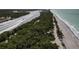 An aerial view displays a sandy beach near lush greenery, highlighting the serene coastal environment at 1156 Lemon Bay Dr, Venice, FL 34293