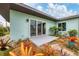 Back patio bordered with vibrant plants and mulch, featuring sliding door access into the home at 1156 Lemon Bay Dr, Venice, FL 34293