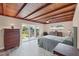 This bedroom features an exposed beam wood ceiling, with sliding glass doors leading to the backyard at 1156 Lemon Bay Dr, Venice, FL 34293