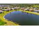 Wide aerial view of neighborhood showing a large pond surrounded by well-maintained lawns and landscaping at 12830 24Th Street E Cir, Parrish, FL 34219