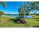 Landscaped backyard with lake views features lush lawn, mature trees, and decorative flowerbeds at 12830 24Th Street E Cir, Parrish, FL 34219